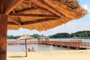 Plażowicze wypoczywający nad zalewem Mrożyczka, w tle molo z platforma widokową