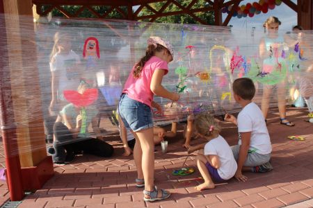 Dzieci malujące farbami po rozwieszonej folii