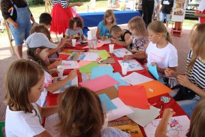 Dzieci siedzące przy stole bawiące się kolorowym papierem
